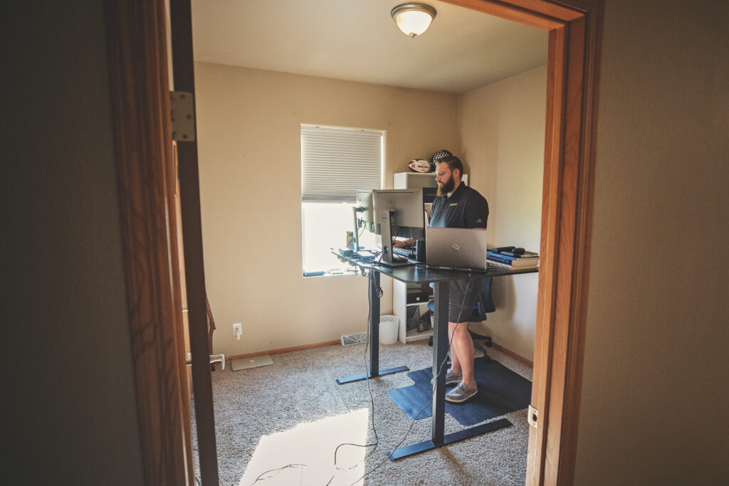 In his Valentine home, Hunter Miller works at a standing desk. His internet connection is fast enough to meet the requirements of his engineering job with Olsson. Photo by Phil & Whitney Mayhew for the Flatwater Free Press