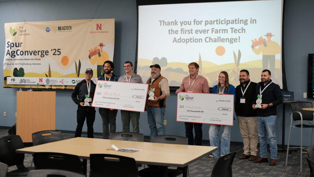 Winners of the farm tech adoption challenge pose for photos with the startups at their tables.