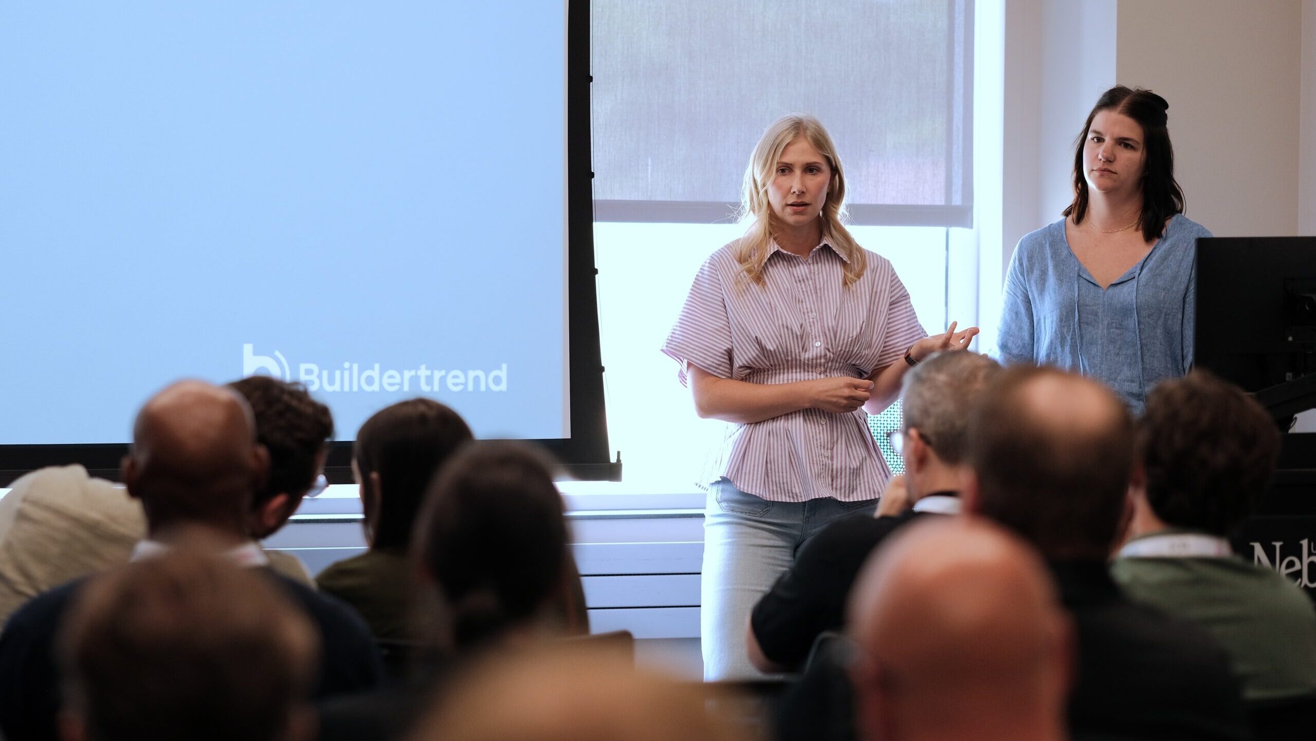 Madeline Anderson (left), director of technical program management, and Tylene Lucas, the staff solutions architect, talk at the 2026 OMAxAI conference about what they learned building a new customer AI chatbot at construction tech company Buildertrend