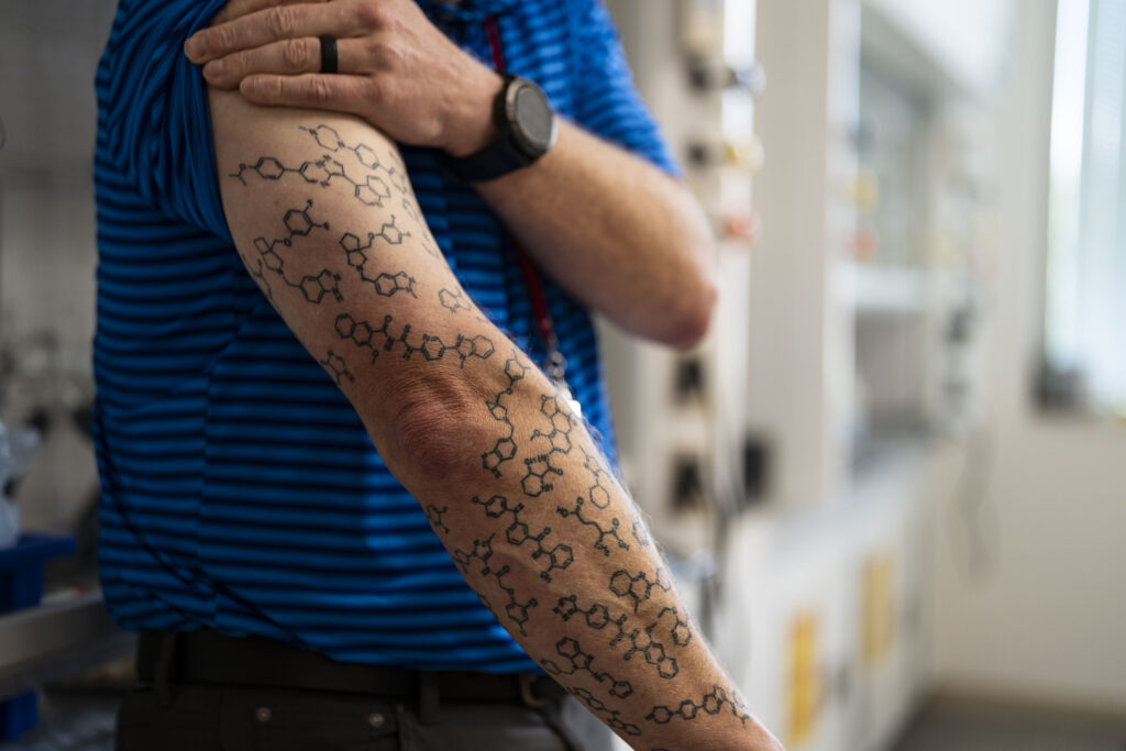 Corey Hopkins, director of the UNMC Center for Drug Design and Innovation, shows the roughly 36 chemicals tattooed on his arm. About four years ago, he started getting patented chemicals created by students in his lab tattooed on his right arm to celebrate drug discovery.