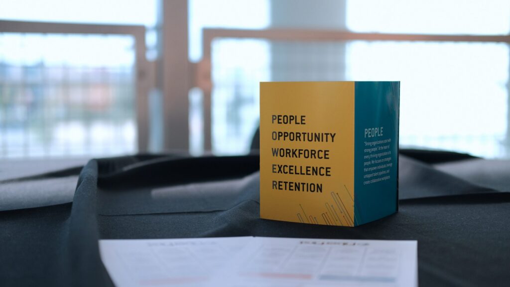 The POWER acronym on a tabletop display card: People, Opportunity, Workforce, Excellence, Retention.