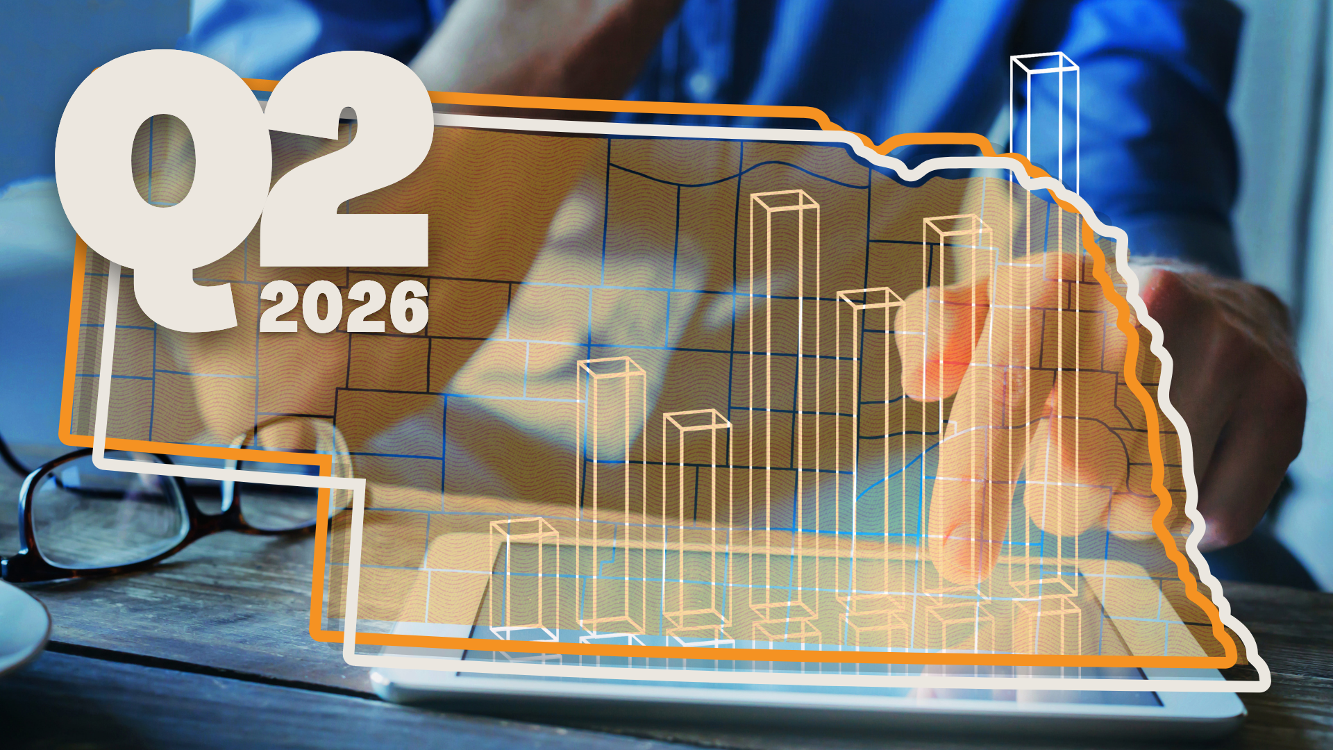 Orange and blue graphic featuring the outline of the state of Nebraska layered on top of a bar graph and a close-up photo of a person crunching numbers at a desk on a tablet. Graphic by Jen Spitzer/Silicon Prairie News